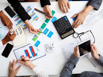 Picture of businessmen's hands on white table with documents, coffee and drafts