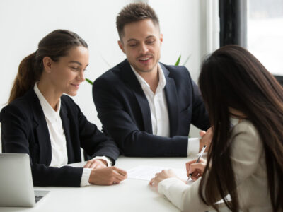 Satisfied HR managers presenting contract to hired female applicant, employee happily signing agreement, candidate closing deal with potential employers. Concept of recruitment, starting new job